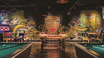 A pool table with a mural in the background, a sign for 2017 courses, and a table with chairs.
