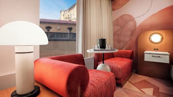 A hotel room with a bed, a desk, a lamp, and a view of the outside.