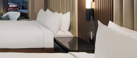 A hotel room with a bed, a bedside table, a chair, and a view of a cityscape.