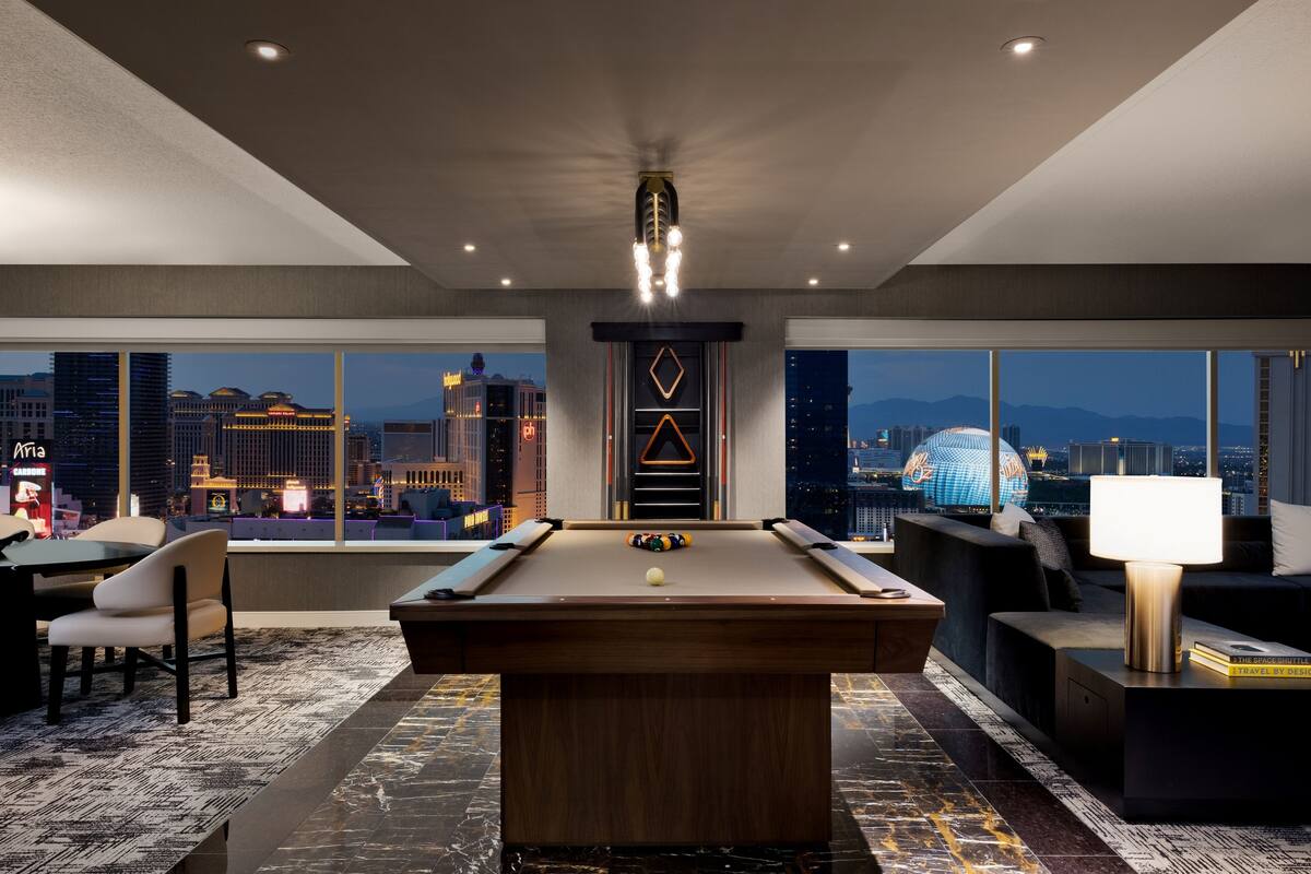 A modern room with a pool table, seating area, and a city view.