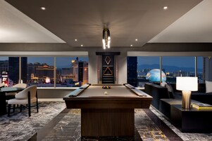 Habitación moderna con mesa de billar, zona de estar y vistas a la ciudad.