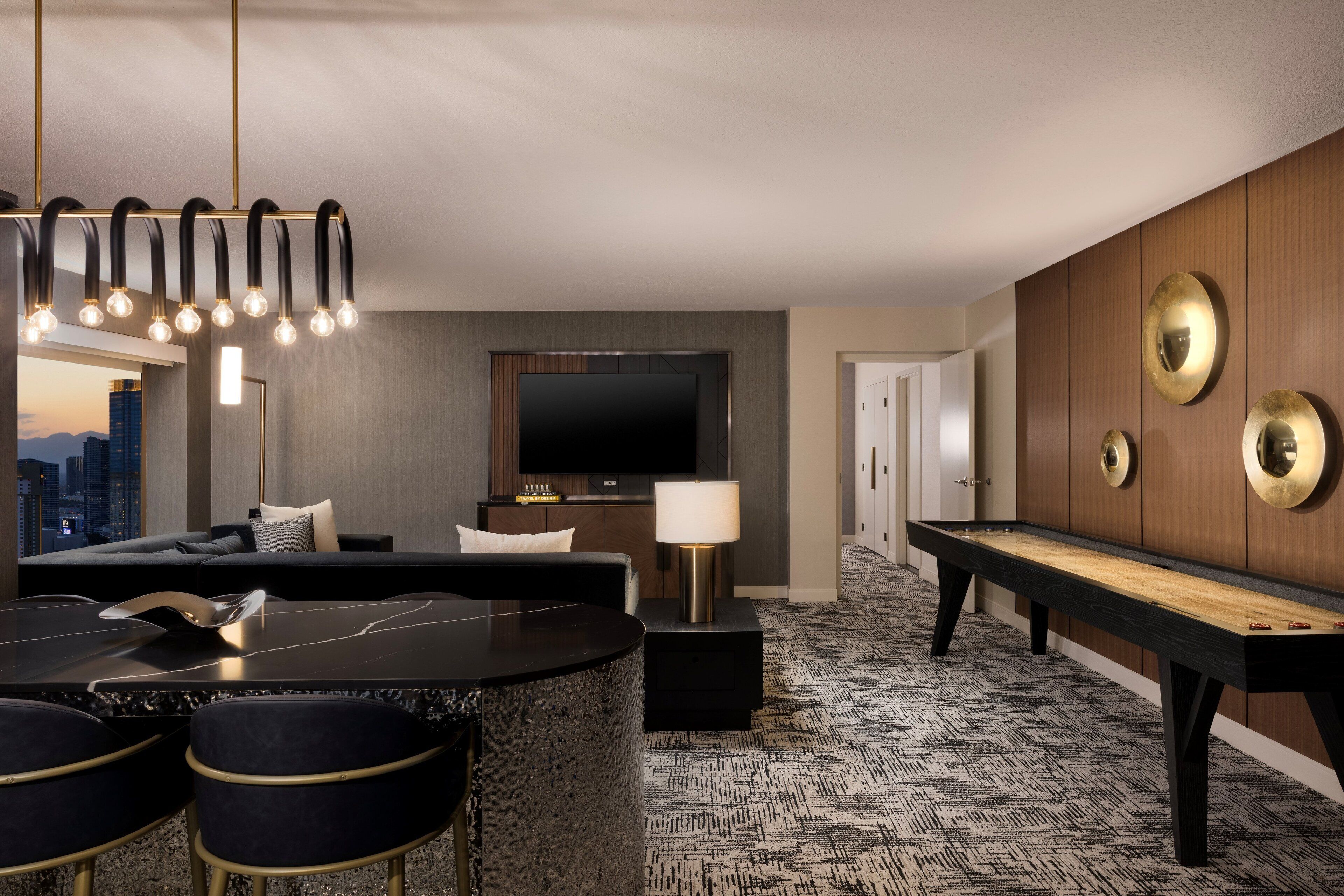 A modern hotel room with a pool table, a sofa, a TV, and a city view.