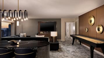 A modern hotel room with a pool table, a sofa, a TV, and a city view.