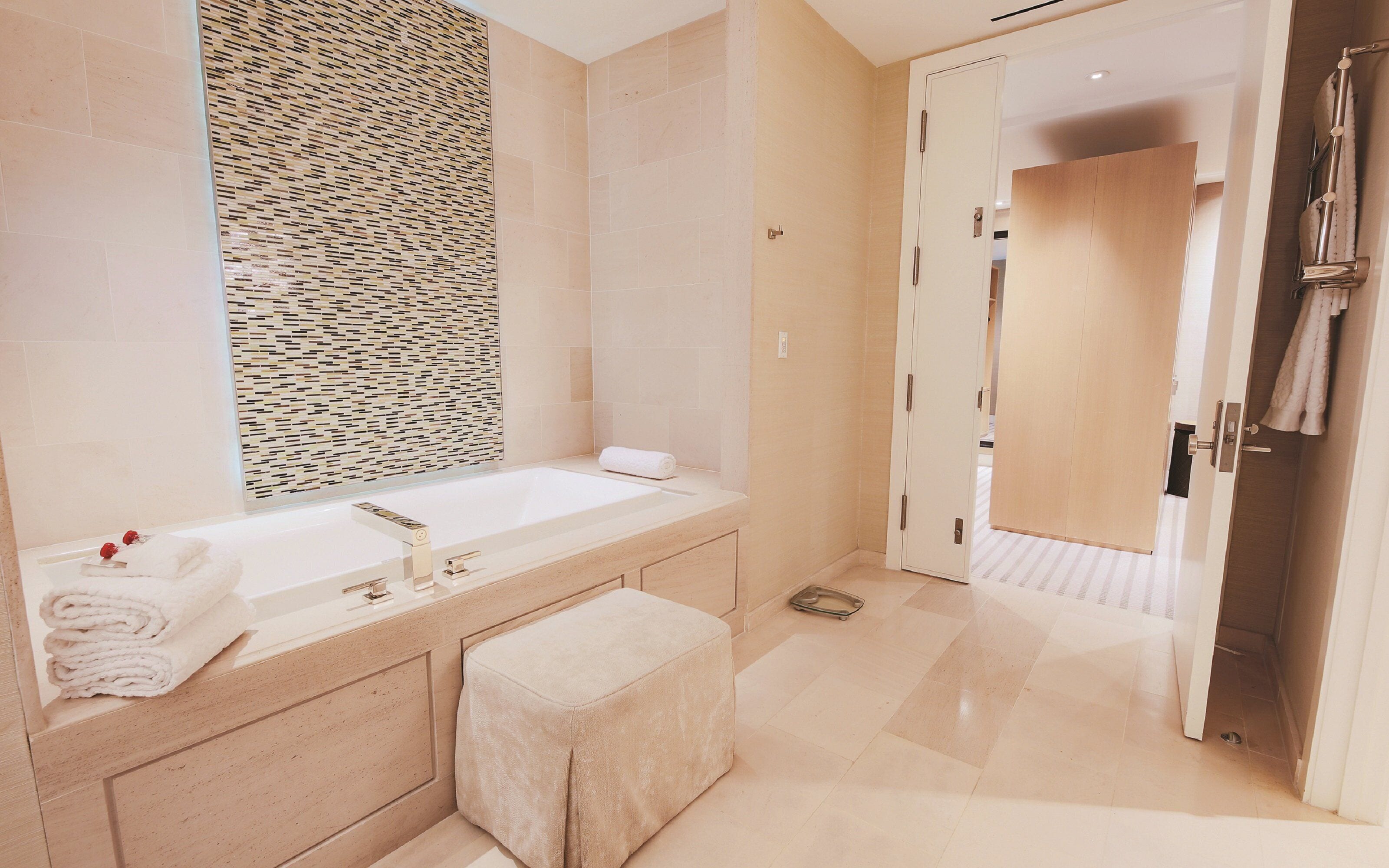 Un baño moderno con una bañera grande, un tocador con espejo y un perchero para toallas.