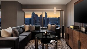 A modern living room with a city view, a black sofa, a round coffee table, and a TV on the right. - MGM Grand Hotel & Casino (Las Vegas)
