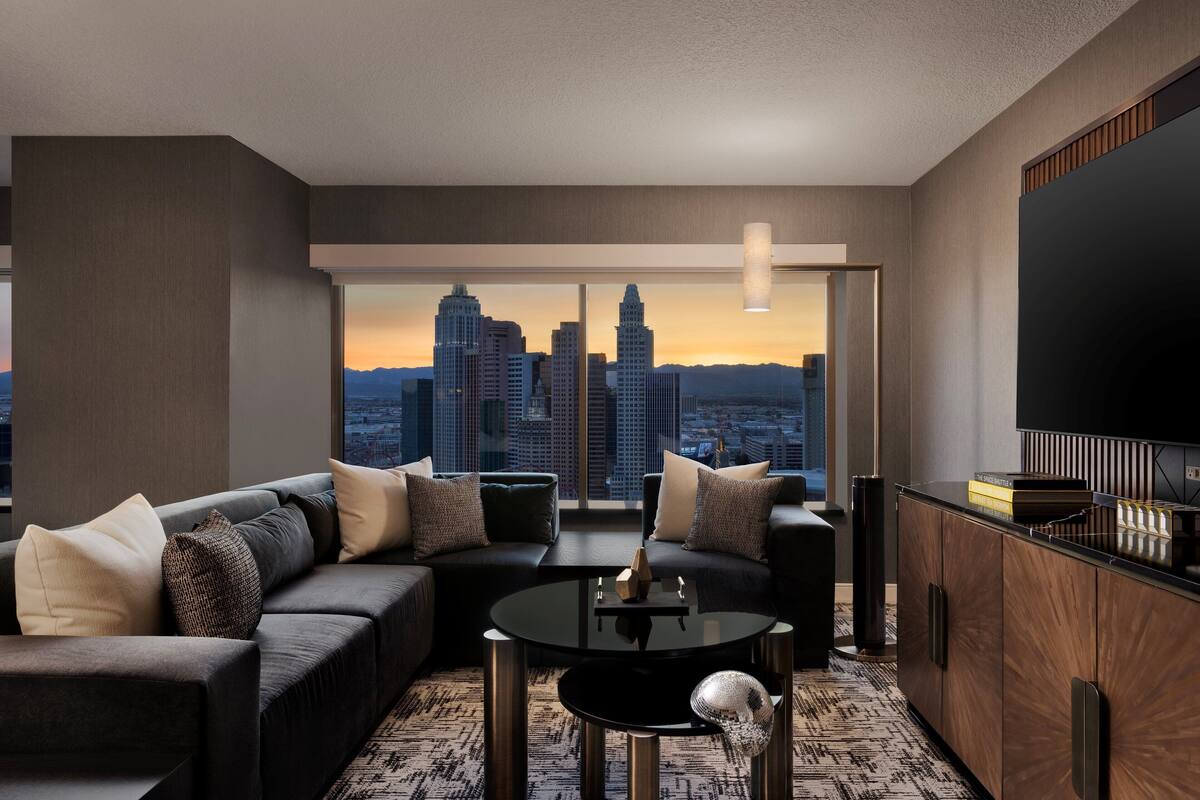A modern living room with a city view, a black sofa, a round coffee table, and a TV on the right.
