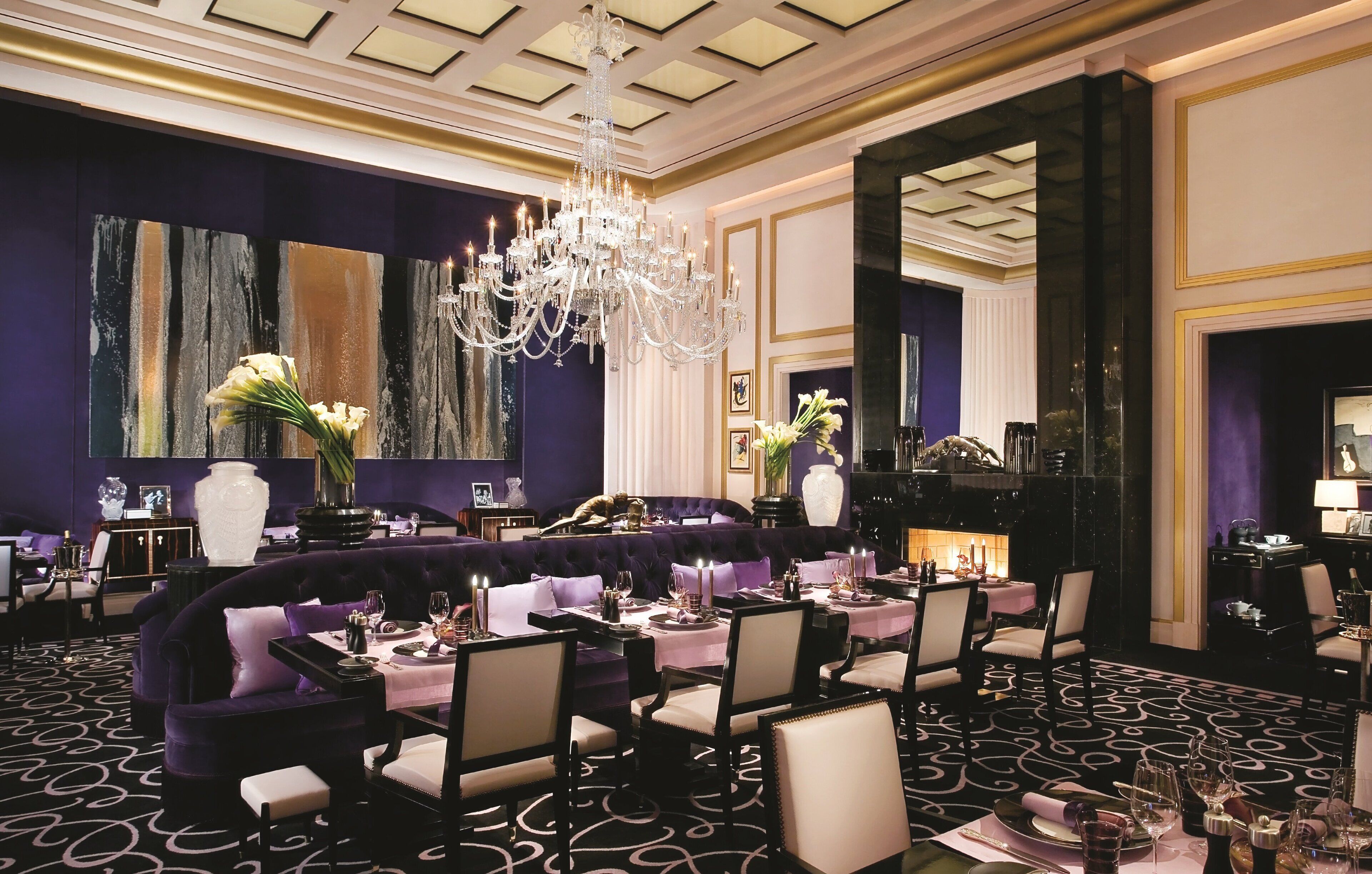 A formal dining room with a chandelier, purple walls, and a large white vase.