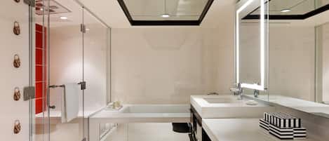 A modern bathroom with a glass shower enclosure, a bathtub, and a vanity with a large mirror.