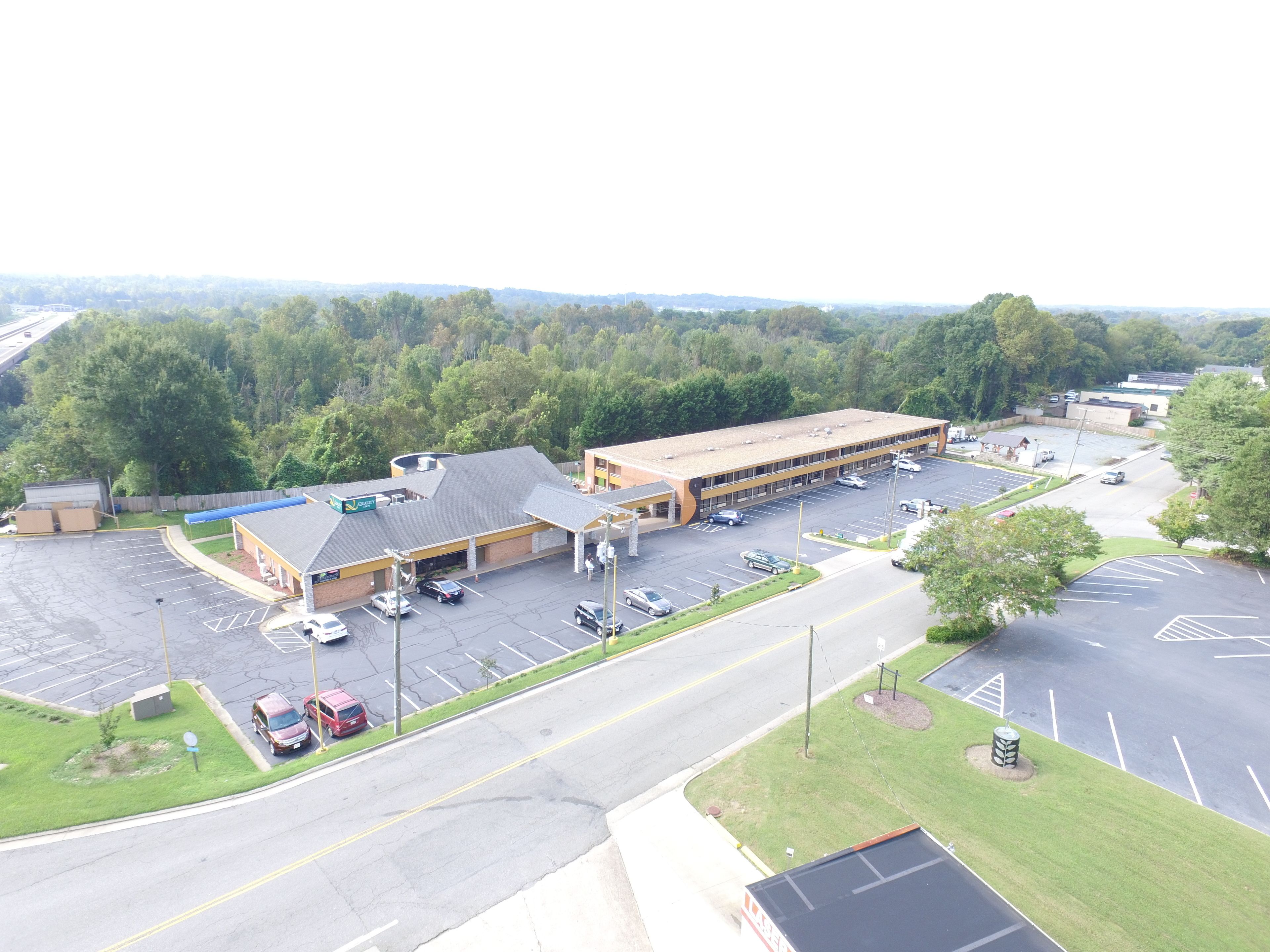 A large parking lot with multiple buildings, including a gas station and a commercial building with a flat roof.