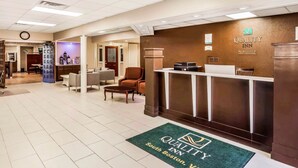 Een hotel receptie met een receptiebalie, een zithoek en een klok aan de muur.