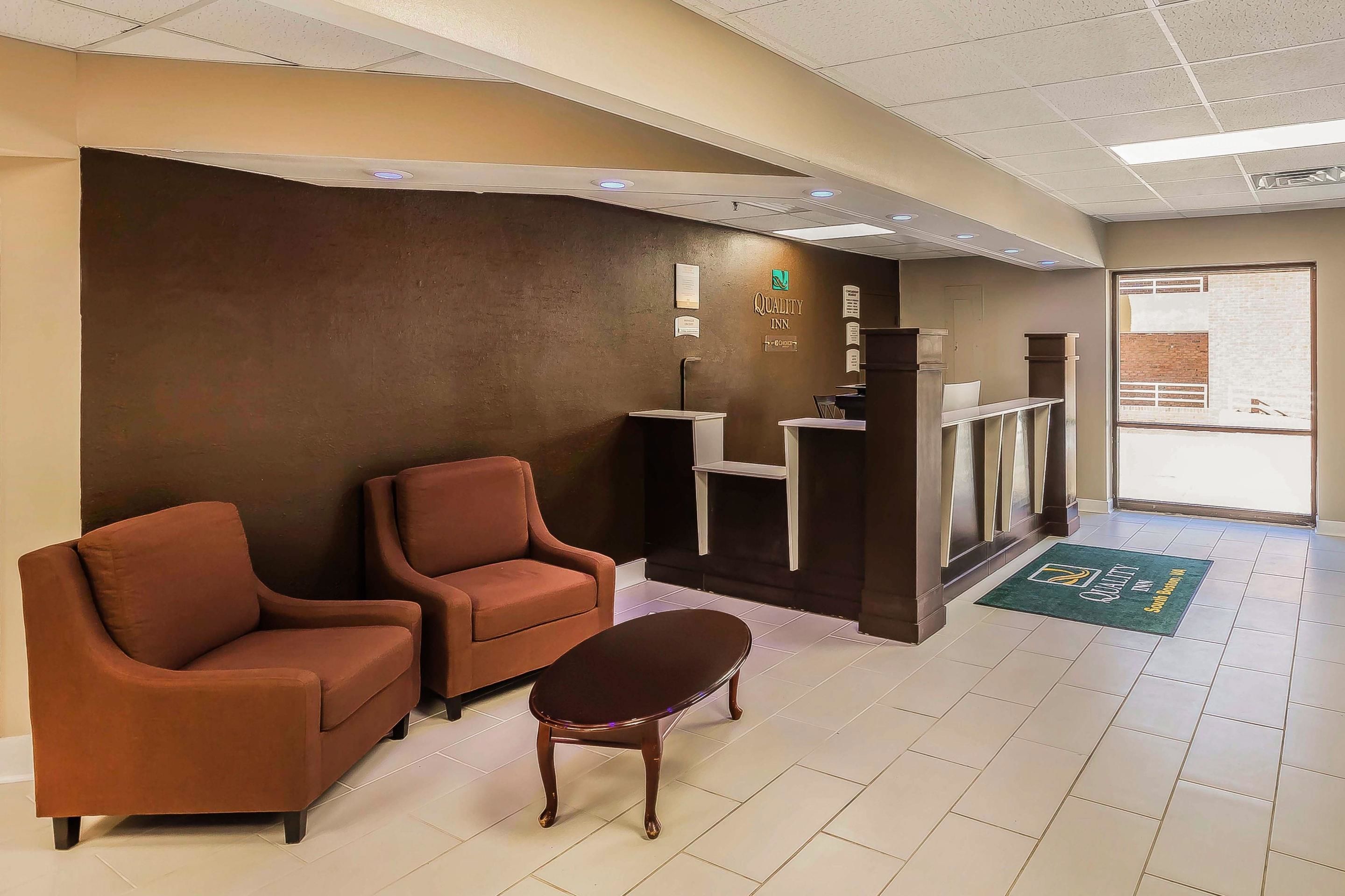 A reception area with two brown sofas, a small wooden table, and a reception desk.