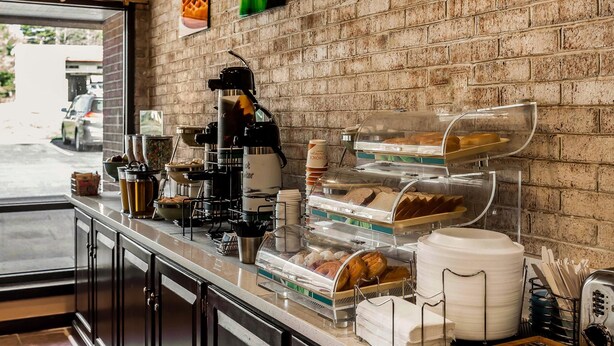 Een ontbijtbuffet met diverse gerechten en een koffieapparaat.