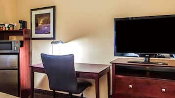 Hotellihuone, jossa on työpöytä, tuoli, televisio, mikroaaltouuni ja pieni kaappi.