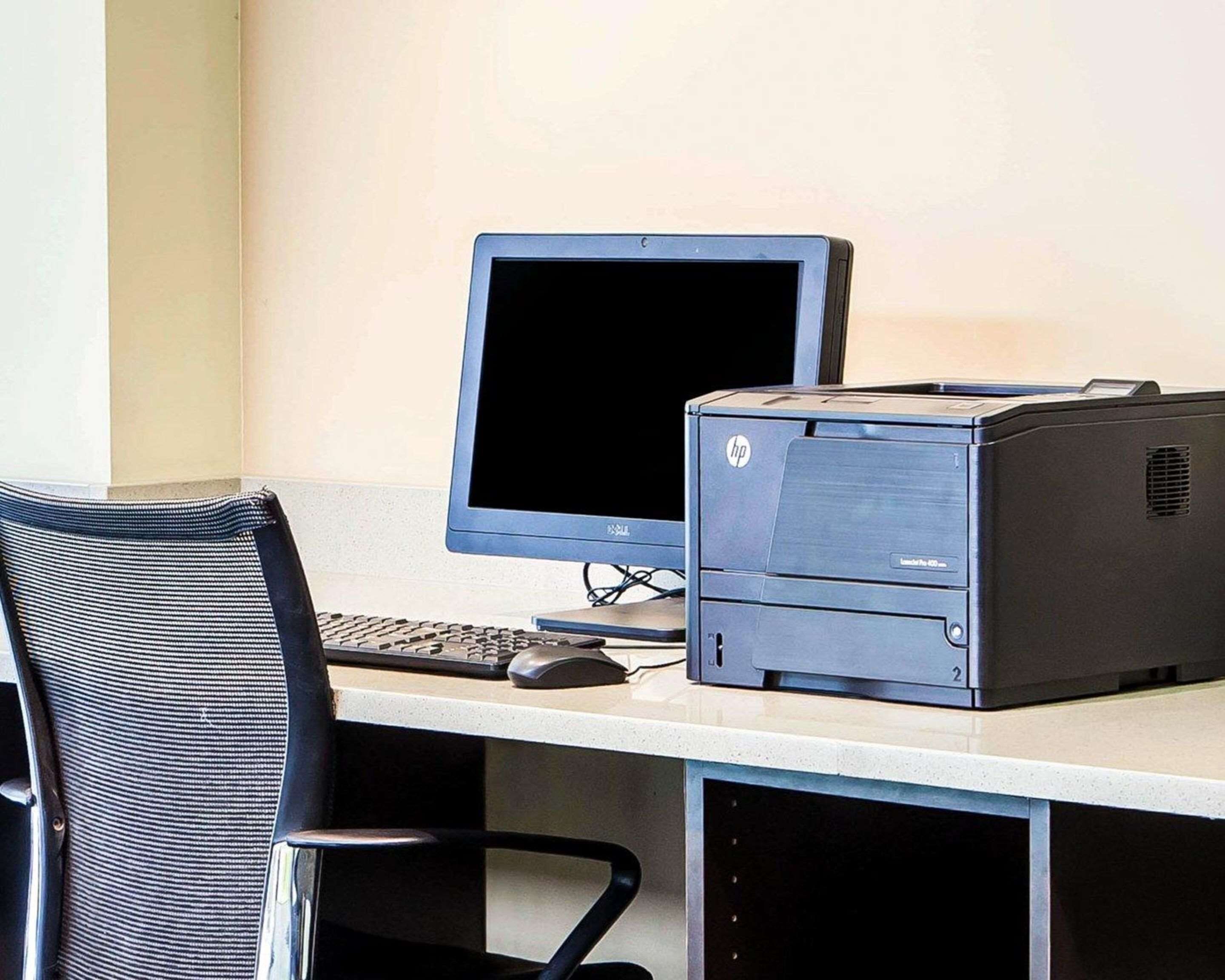 Ein Computertisch mit Bildschirm, Tastatur, Maus und einem HP-Drucker.