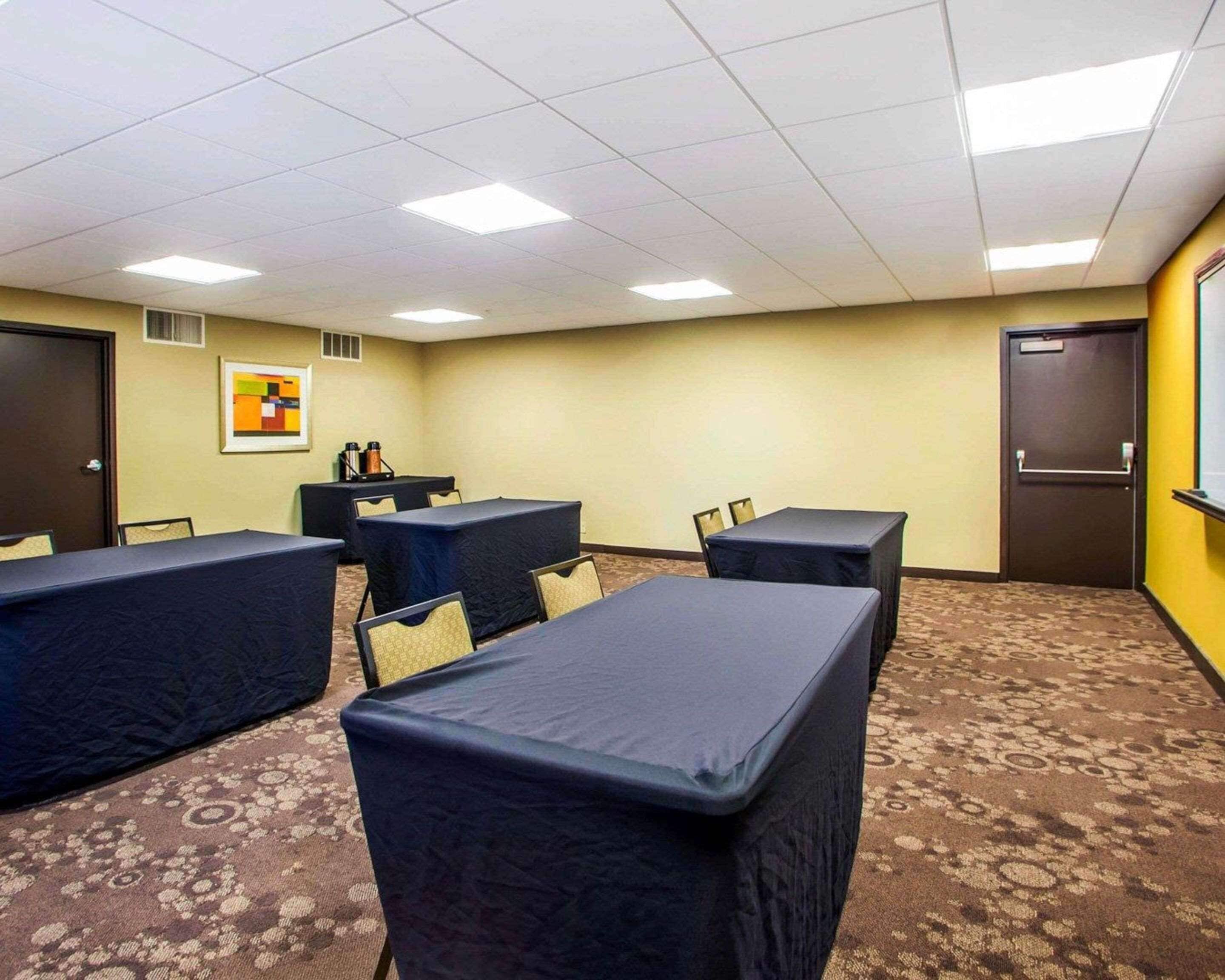 A conference room with multiple tables and chairs, a framed picture on the wall, and a carpeted floor.