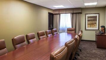 A conference room with a long wooden table surrounded by leather chairs, a carpeted floor, and a painting on the wall.