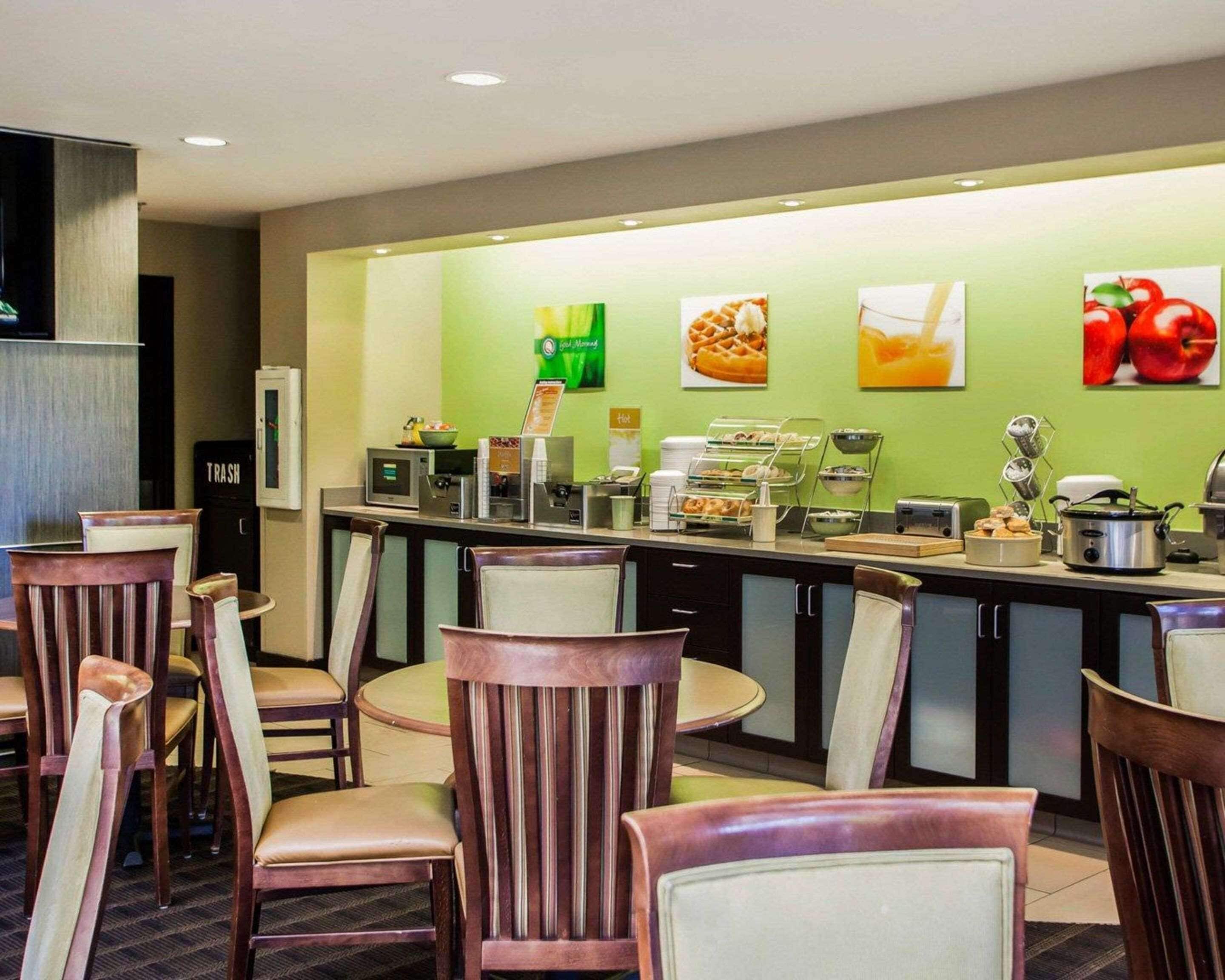 Un comedor de hotel con un mostrador de buffet, sillas y un bote de basura.
