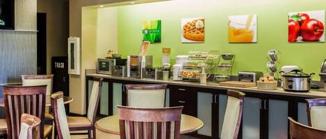 Un comedor de hotel con un mostrador de buffet, sillas y un bote de basura.