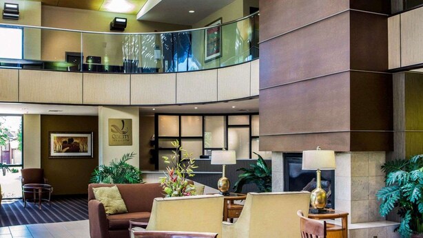 Eine großzügige Lobby mit hoher Decke, einer Sitzecke mit Sofa und Sesseln, einem kleinen Tisch und einem Kamin.