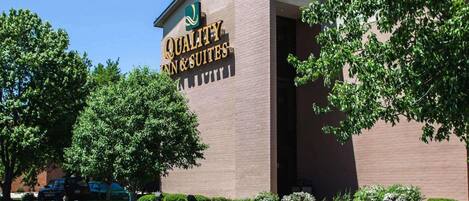 A brick building with a sign for 'Quality Inn & Suites' on the facade.