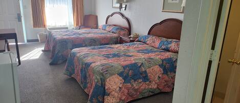 Habitación de hotel con dos camas, un escritorio y una silla.