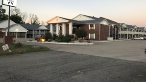 A hotel with a sign for The Blue Ribbon INN & Suites, featuring a brick facade, large windows, and a covered entrance. - Blue Ribbon Inn and Suites (Sallisaw)