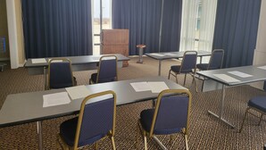 A conference room with a carpeted floor, blue curtains, and a chandelier. - Blue Ribbon Inn and Suites (Sallisaw)