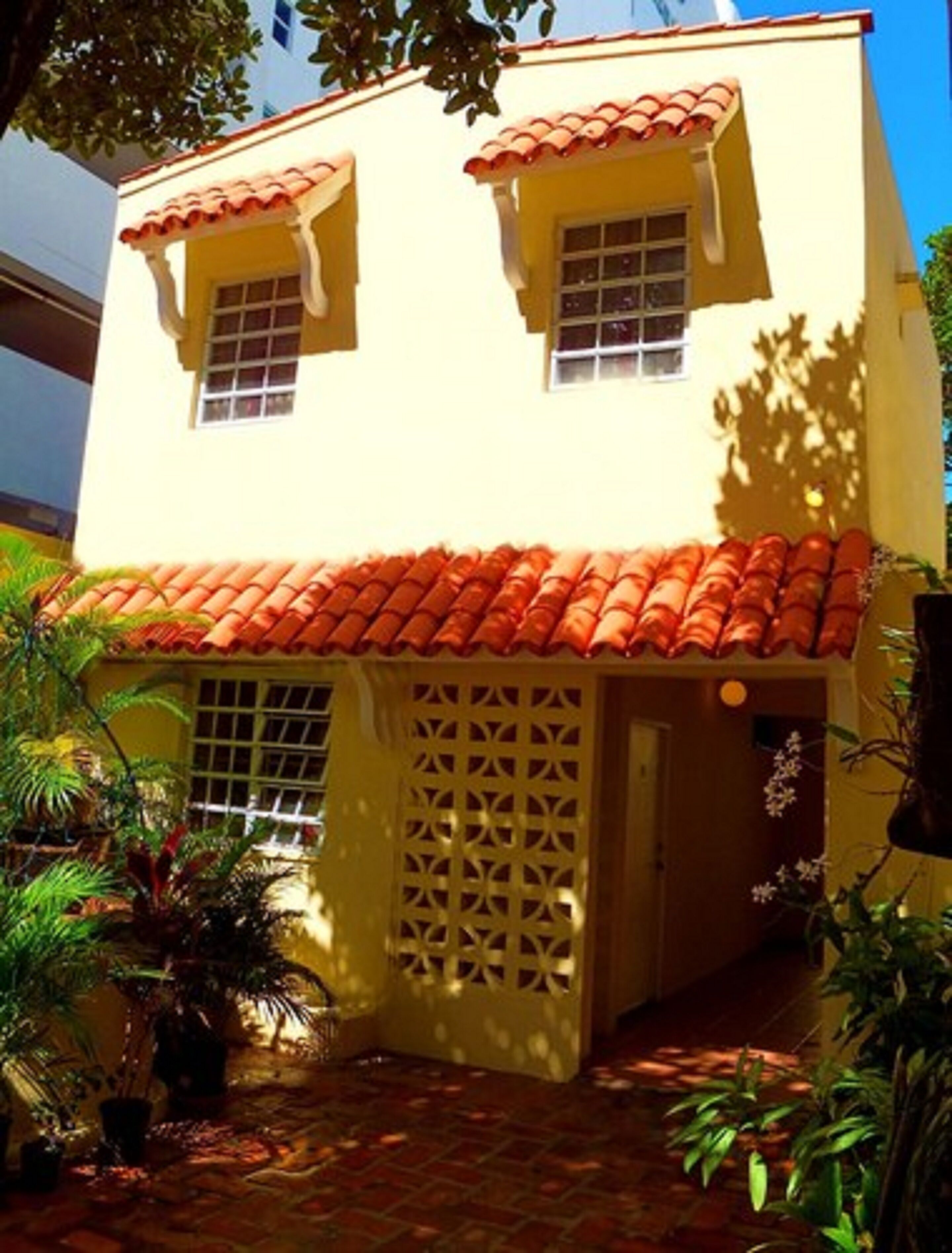 A two-story building with a red-tiled roof and a lattice door.