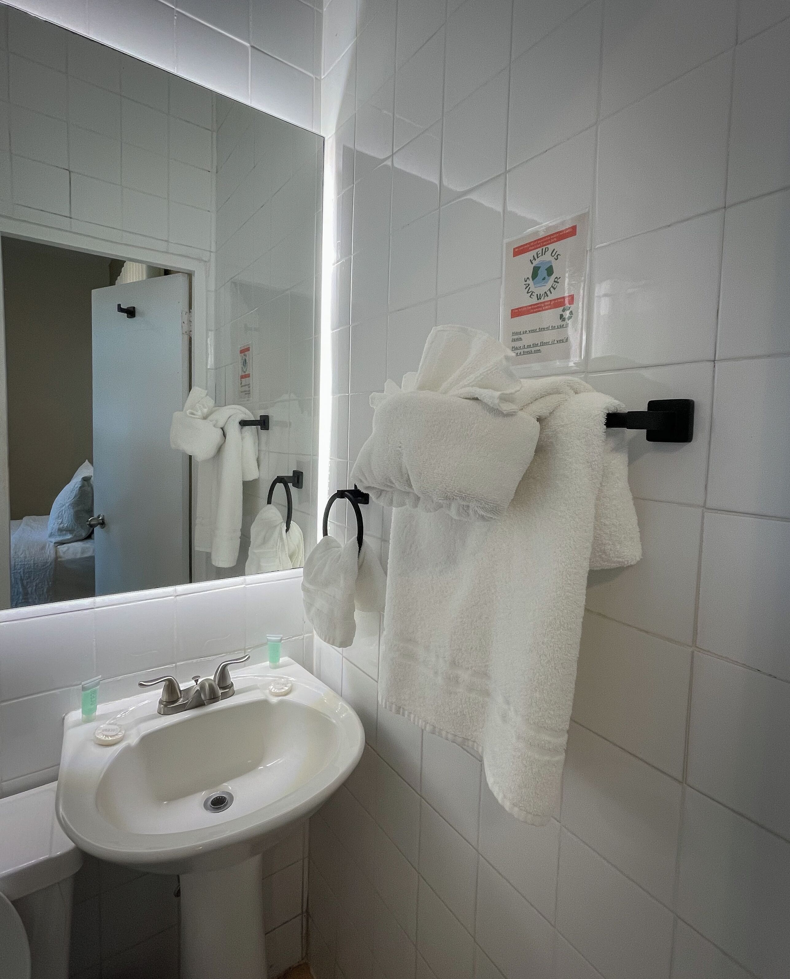 Un baño con un lavabo blanco, un espejo y un perchero para toallas.