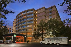 A multi-story hotel with a curved facade, a parking lot, and a delivery truck parked in front. - Embassy Suites by Hilton Chicago O'Hare Rosemont (Rosemont)