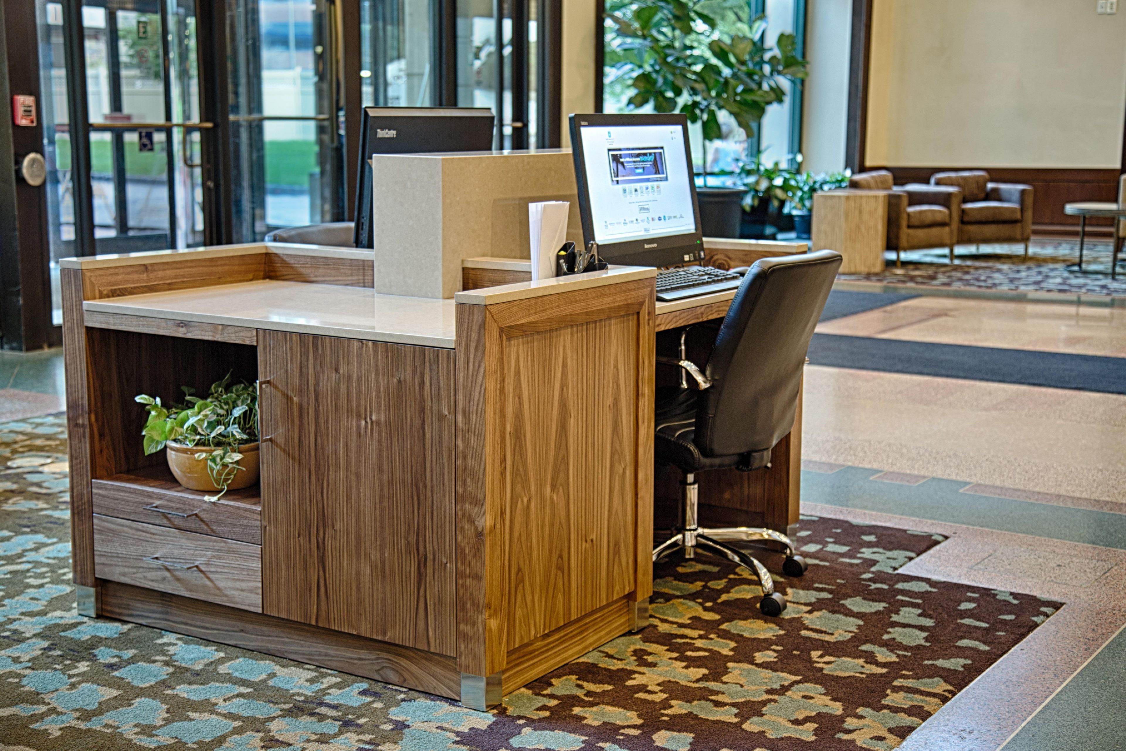 A reception desk with a computer, a chair, and a potted plant.