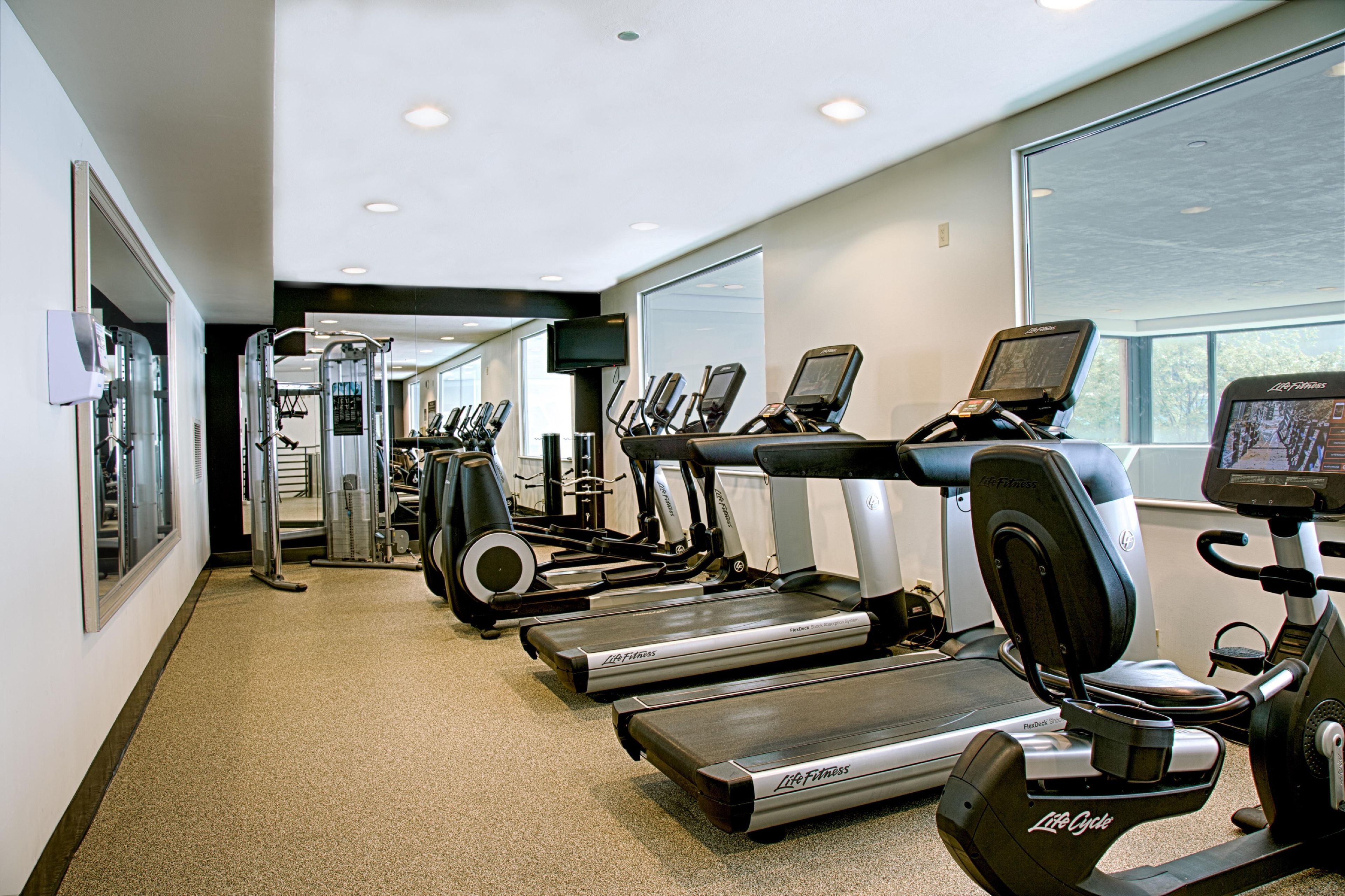 Et fitnesscenter med løbebånd, crosstrainere og styrkeudstyr.