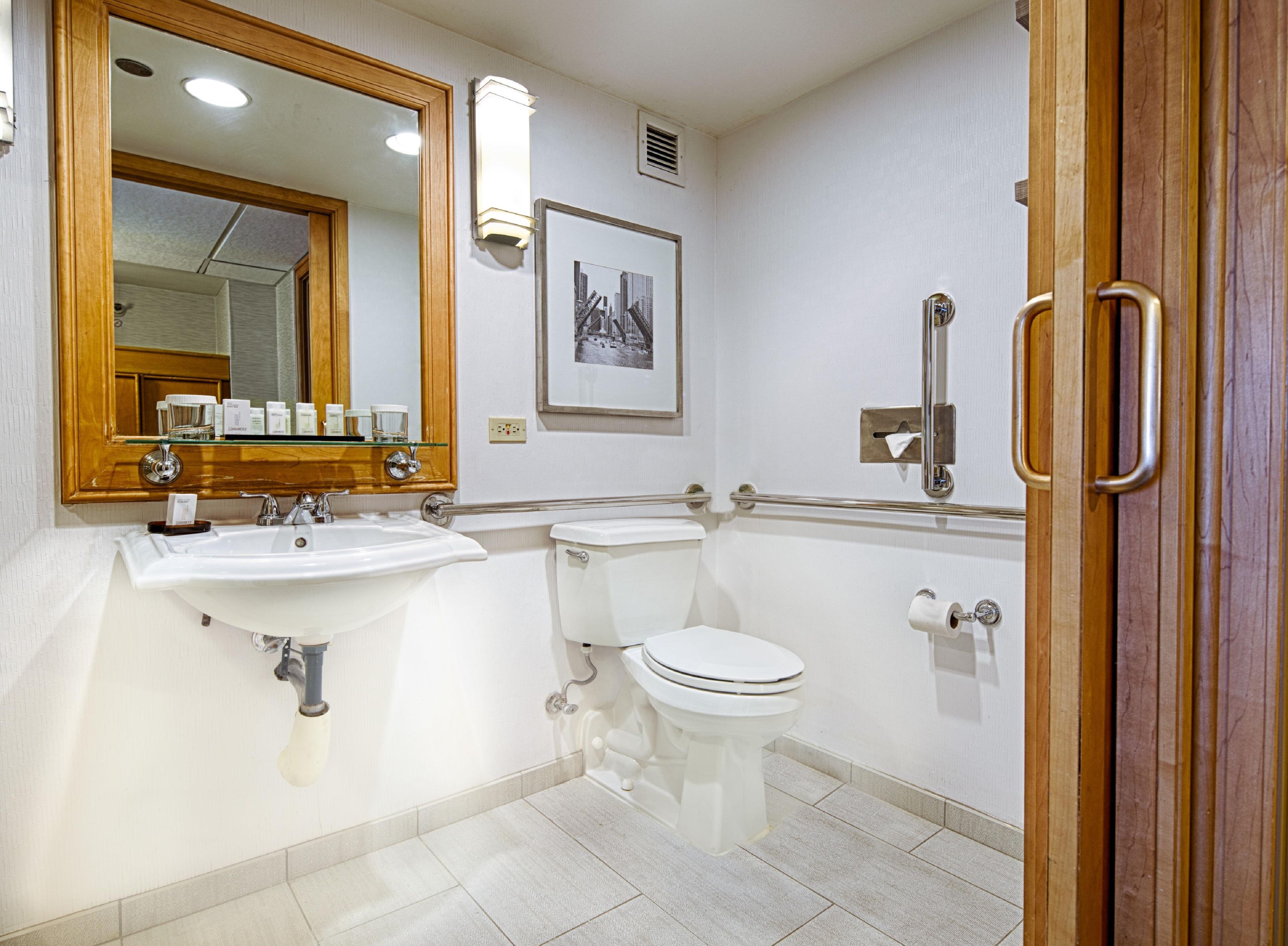 Un baño con lavamanos, inodoro y barra de apoyo.