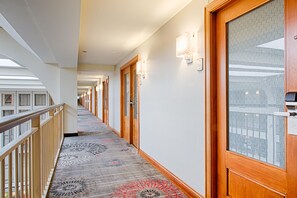 A hotel corridor with wooden doors, patterned carpet, and a railing on the left. - Embassy Suites by Hilton Chicago O'Hare Rosemont (Rosemont)