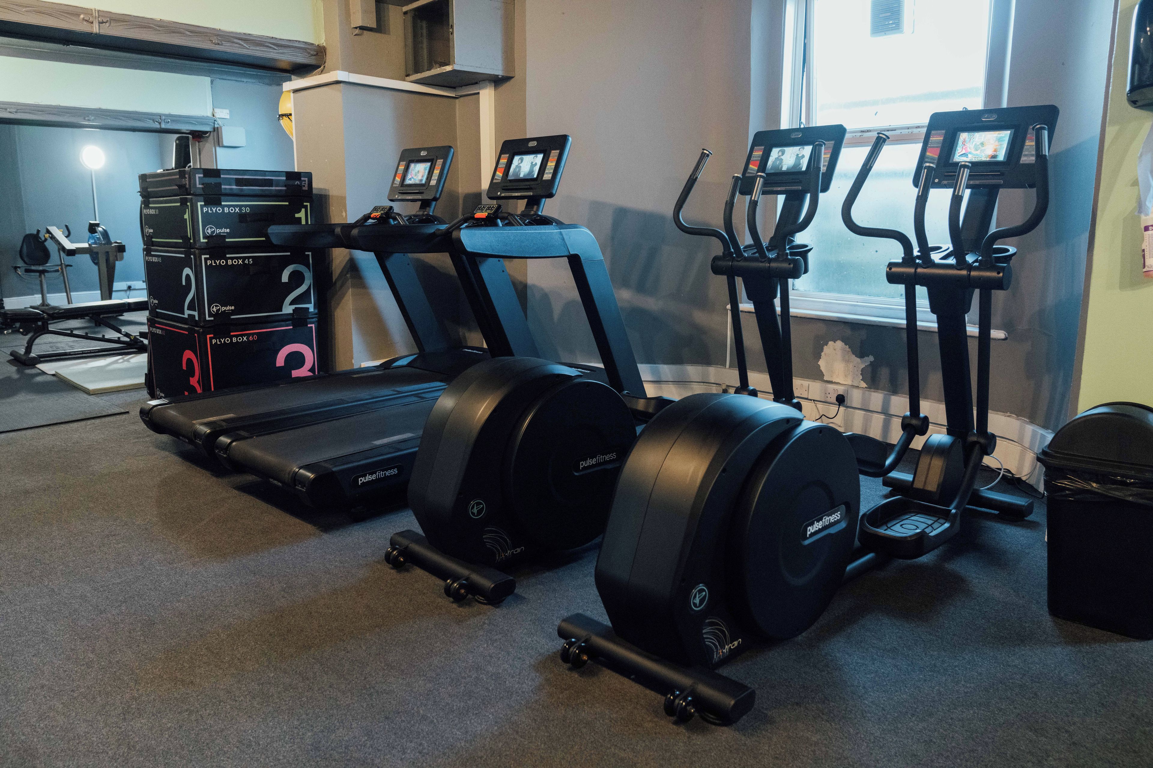 A gym with treadmills, elliptical machines, and stationary bikes.