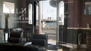 A modern interior with leather seating, a glass door entrance, and a view of a bridge. - Queens Hotel (Brighton)