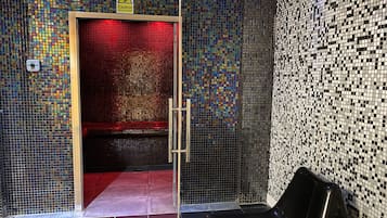 A tiled wall with a caution sign, a door with a red frame, and a black object on the floor.
