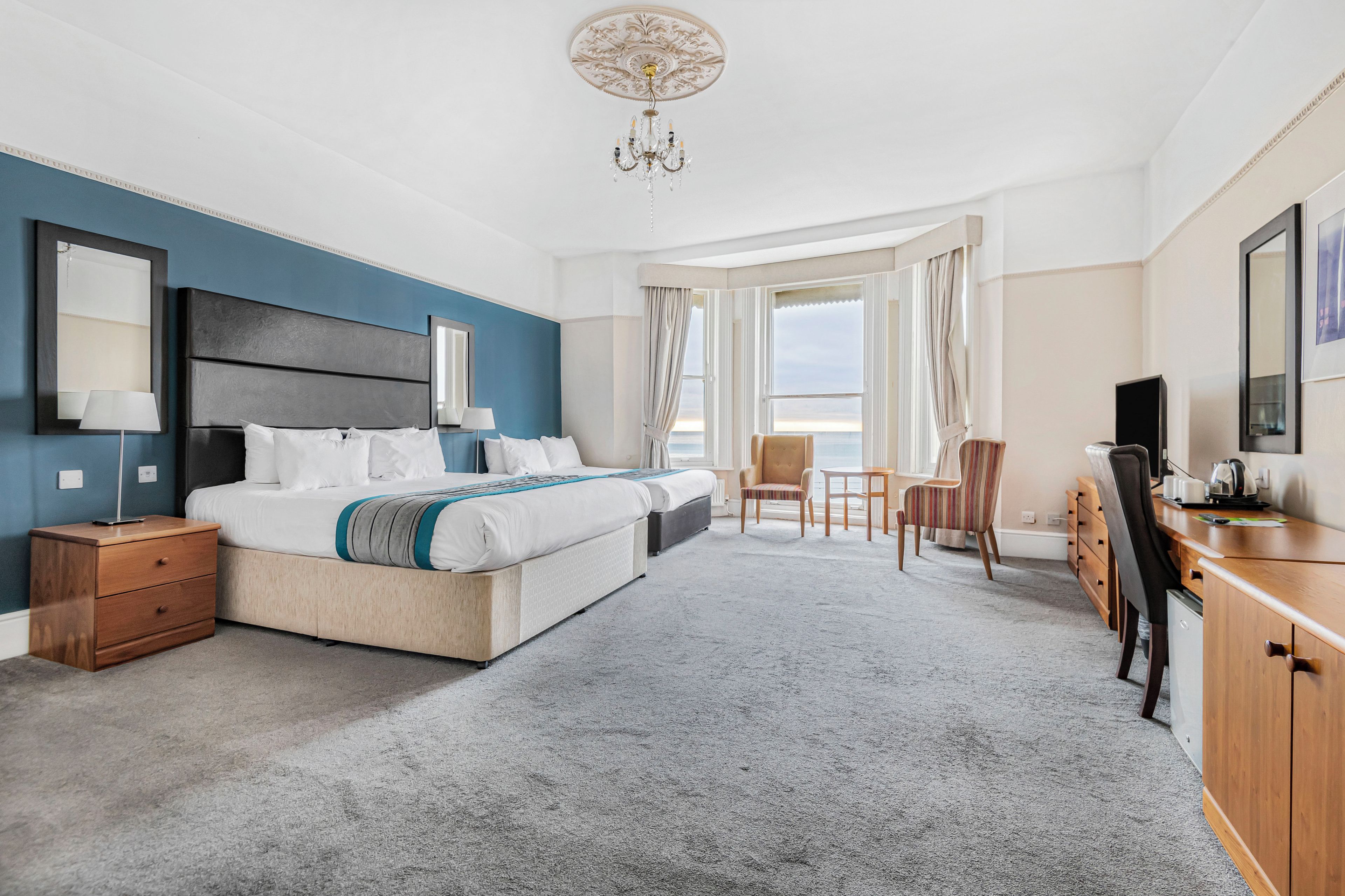 A hotel room with a large bed, a desk, a chair, and a television.