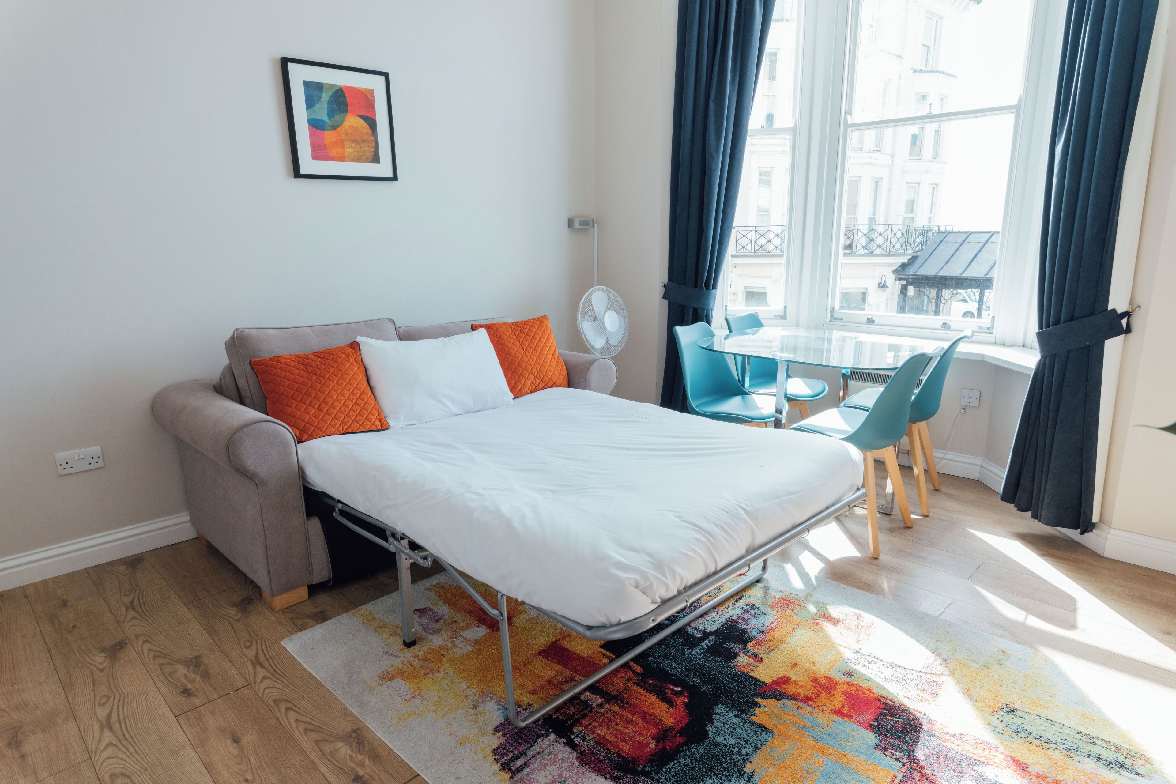 A modern bedroom with a bed, a sofa, a small table, and a chair.