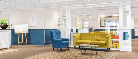 A modern interior with a blue armchair, a yellow sofa, and a patterned rug.