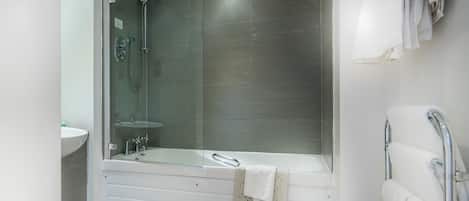 A modern bathroom with a glass-enclosed shower, a white bathtub, and a white sink.