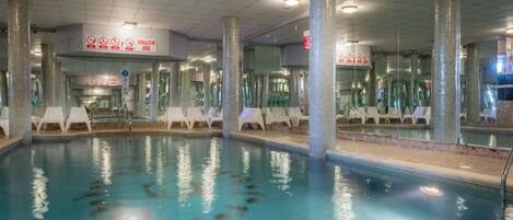An indoor swimming pool with clear signage, including a 'shallow end' warning.