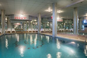 Una piscina interior con señalización clara, incluyendo una advertencia sobre la zona poco profunda.