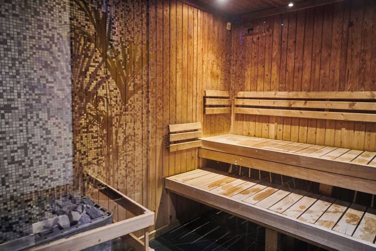 A sauna with wooden benches and a mosaic wall.