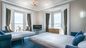 A hotel room with two beds, a TV, and a view of the sea. - Queens Hotel (Brighton)