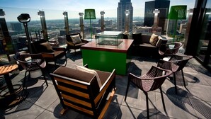 Une terrasse sur le toit, avec une table en verre, des sièges confortables et une vue sur le paysage urbain.