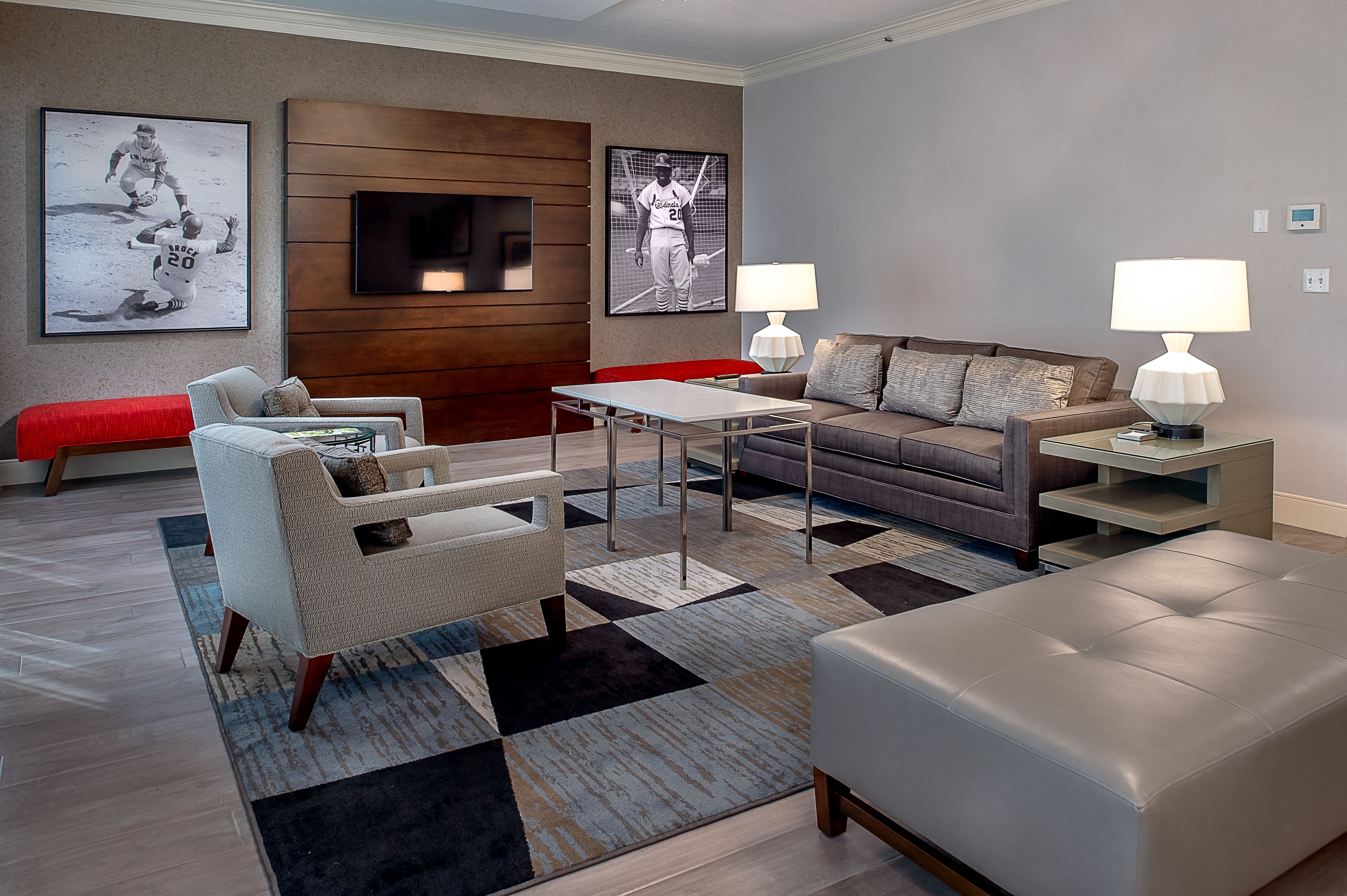 A modern living room with a sofa, armchair, and ottoman, a coffee table, and two lamps.