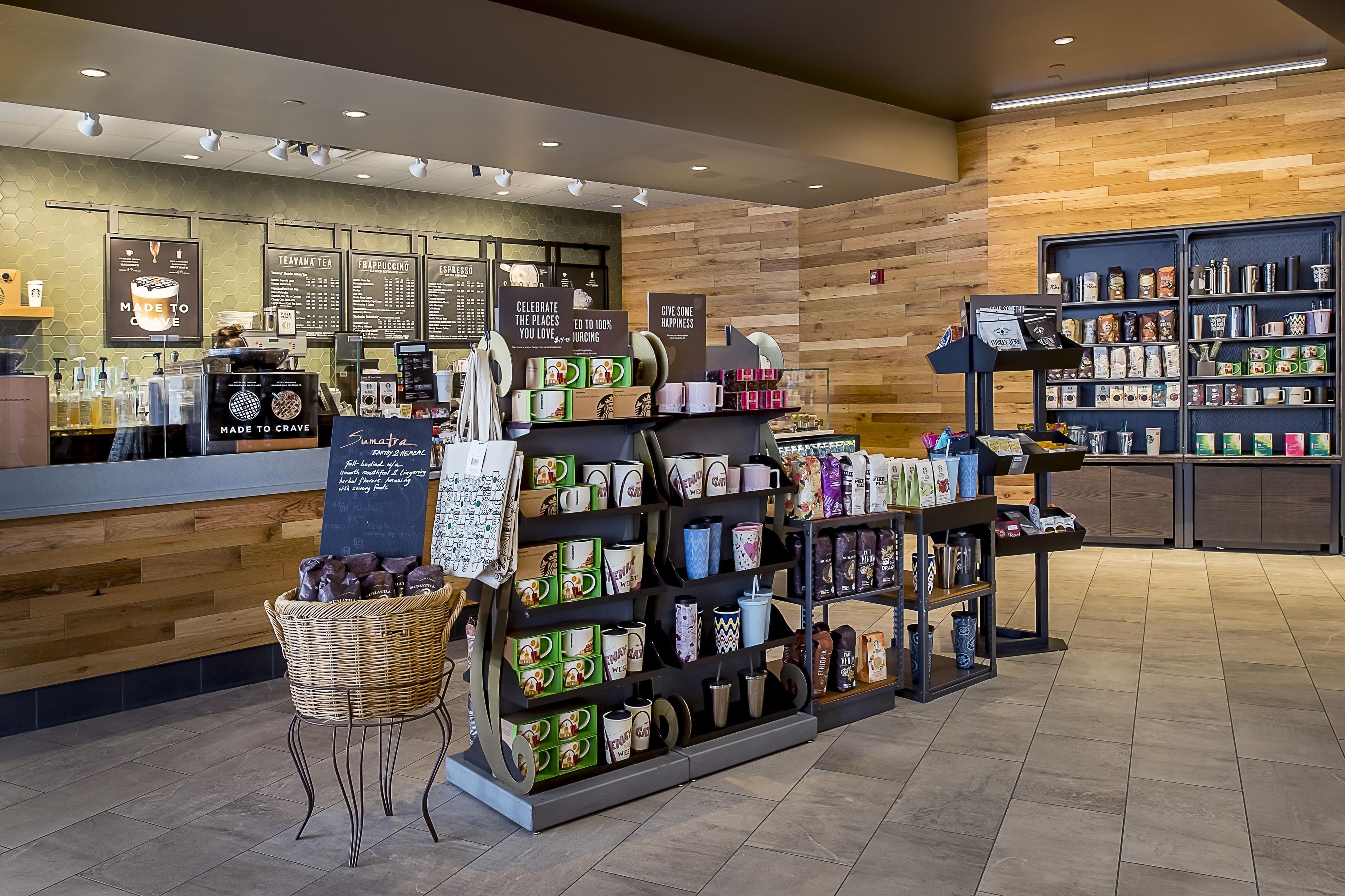 A coffee shop interior with a counter, menu boards, and shelves stocked with coffee products and branded merchandise.