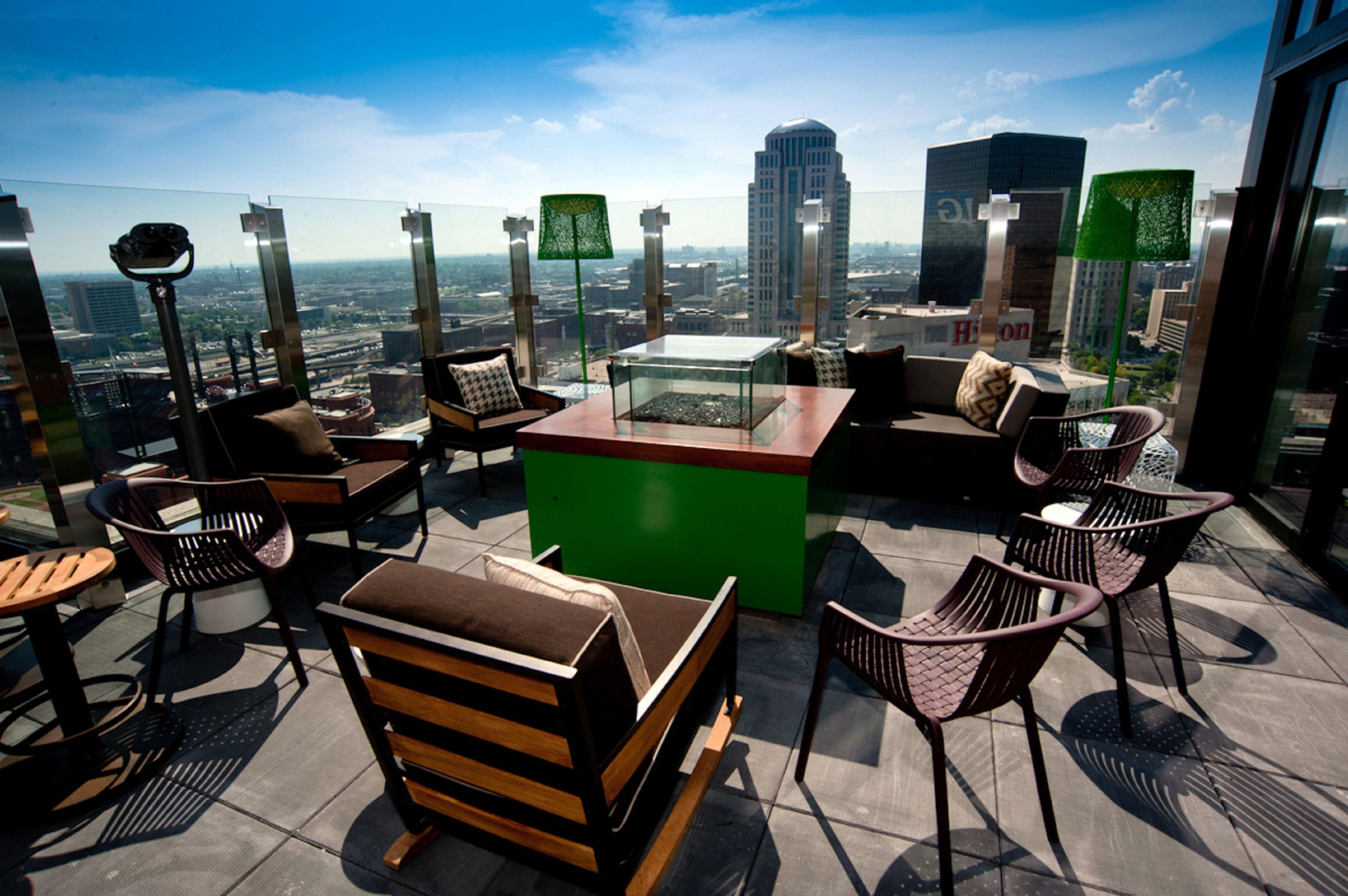 A rooftop terrace with a seating area, a coffee table, and a view of the cityscape.