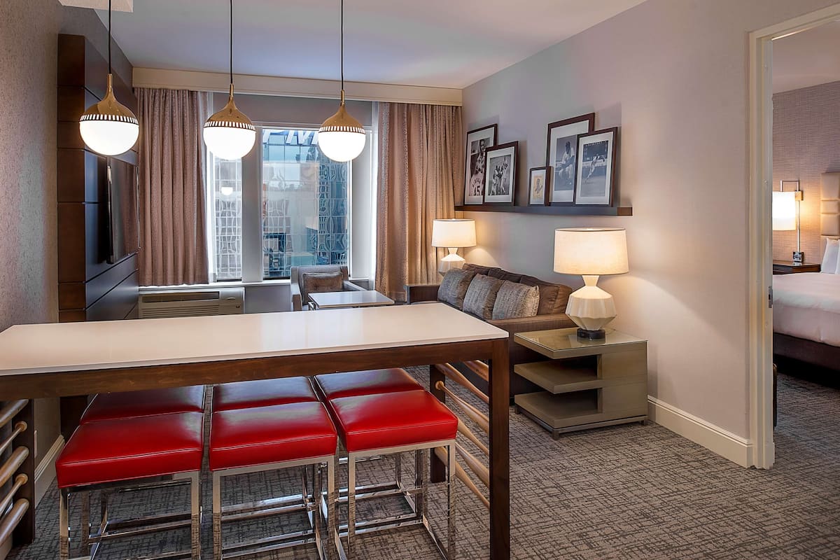 Una habitación de hotel con comedor, sofá, cama y vistas a la ciudad.